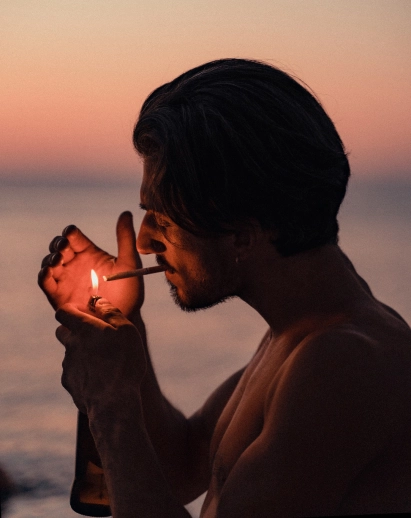 Portrait of a man light a cigarette behind the sunset